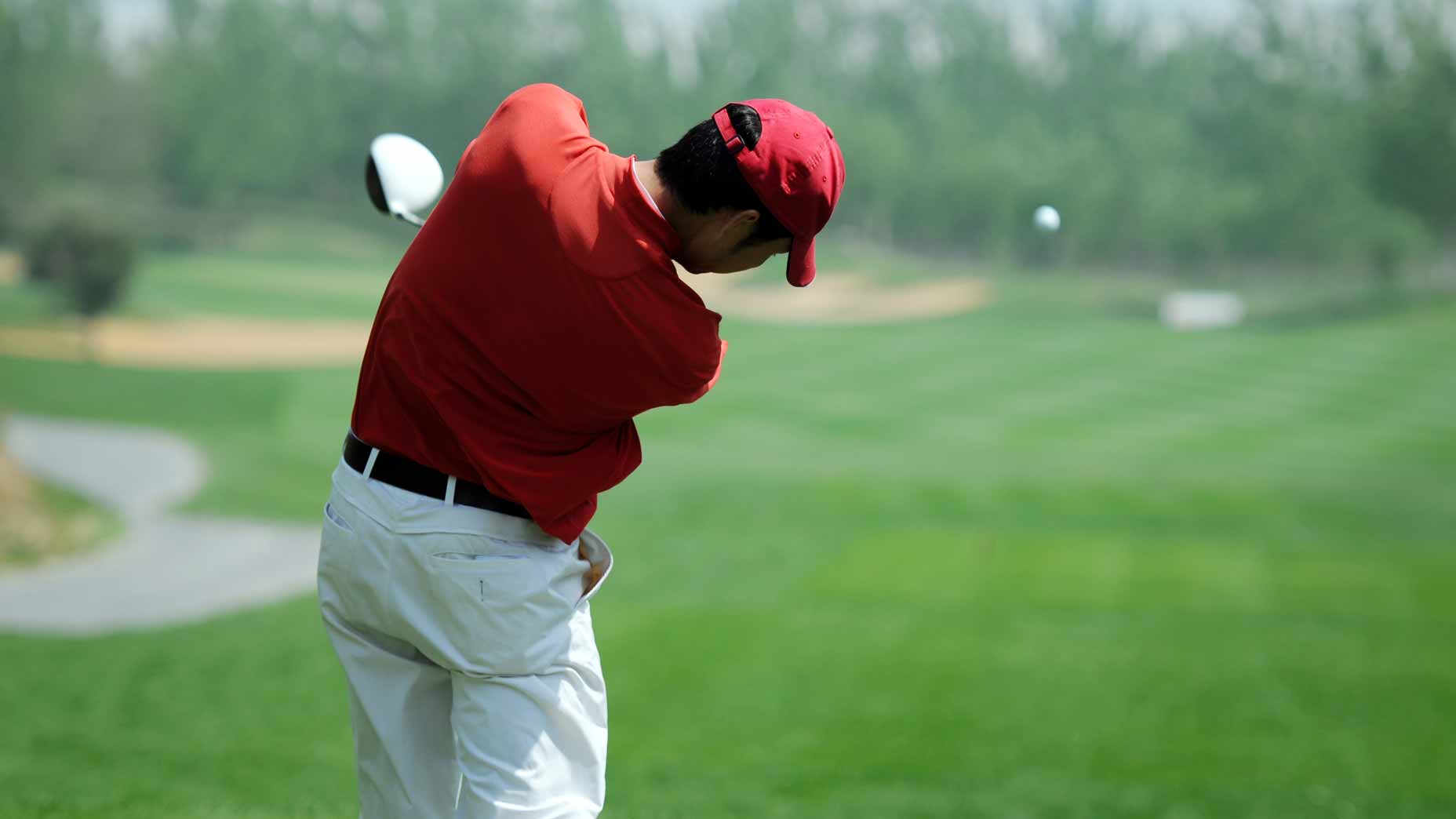 golfer in red shirt swings driver